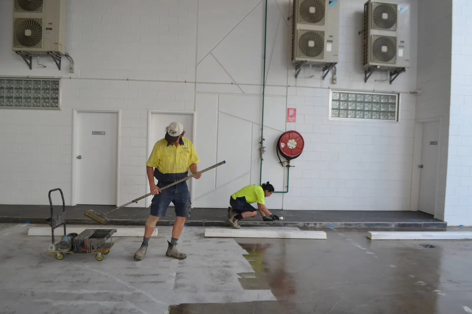 Applying a professional floor coating with a squeegee and roller